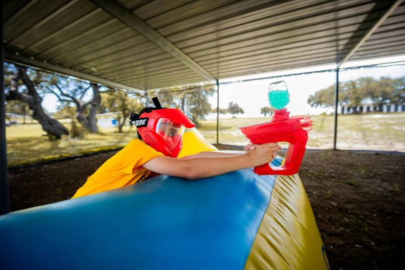 Garçon derrière un mur gonflable muni de son pistolet en plastique